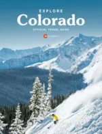 Colorado Travel Guide: A scenic view of the Colorado Rocky Mountains with a clear blue sky and lush green forests in the foreground.