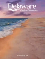 Delaware Travel Guide: A scenic view of the Delaware coastline with sand dunes and a lighthouse in the distance.