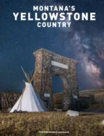 Montana Travel Guide: A scenic view of a glacial lake surrounded by rugged mountain peaks and evergreen trees in Montana.